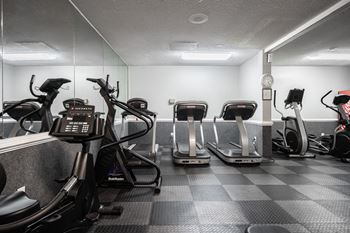 A gym with treadmills, elliptical machines, and a weight machine.